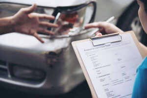 Insurance-agent-filling-out-personal-accident-claim-form-after-car-accident-with-visible-vehicle-damage